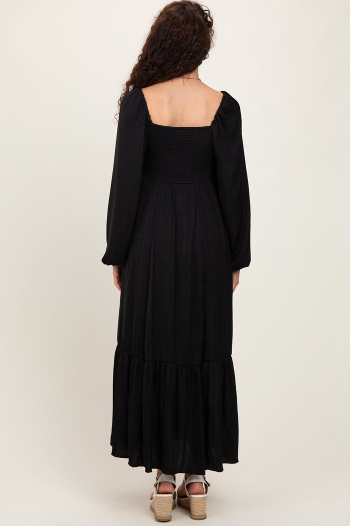 woman wearing a black long sleeve maxi dress with a smocked bodice and tiered skirt, shown from the back