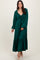 woman wearing a green maxi dress with a knotted bodice and puff sleeves, standing with a smile on a neutral background