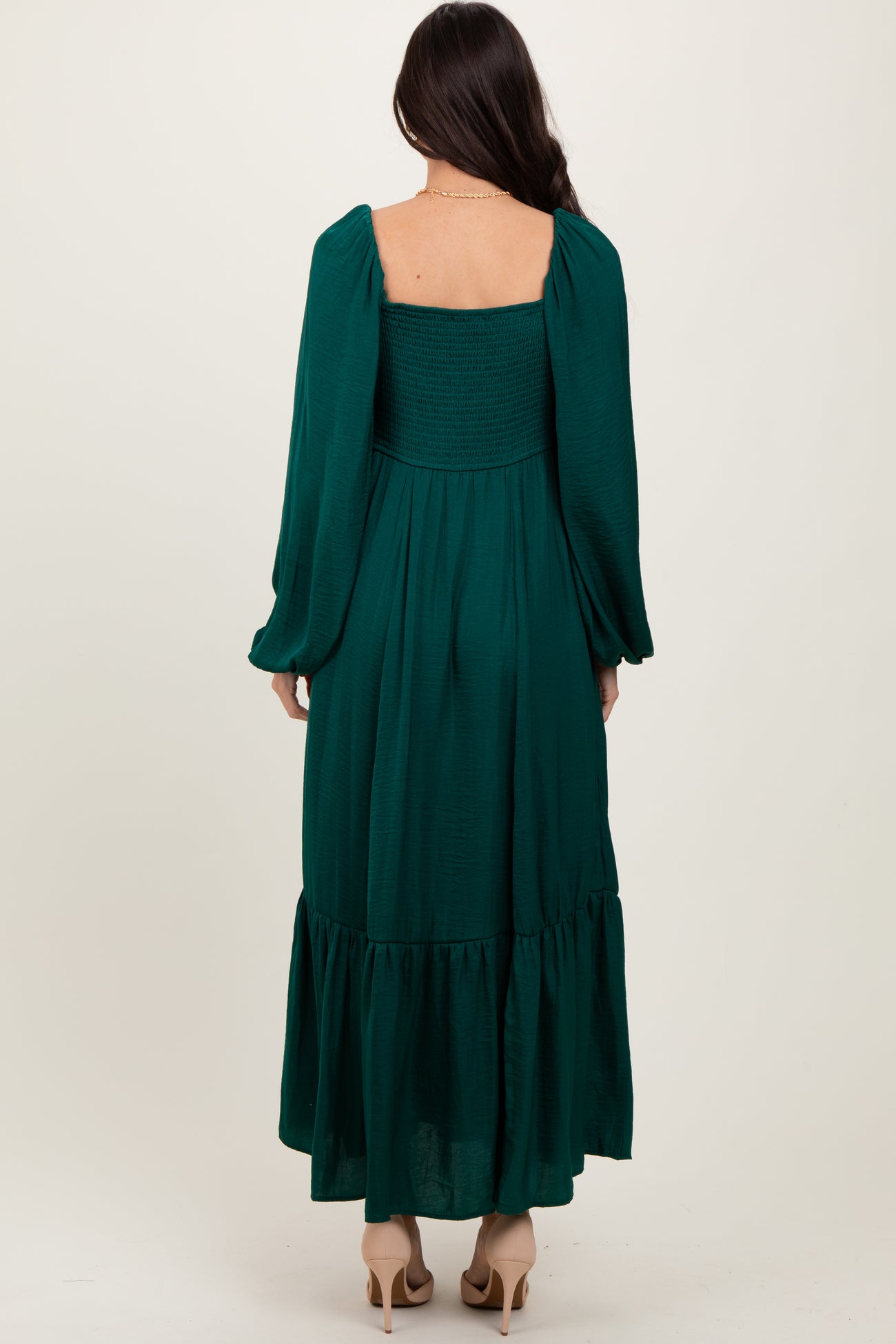 woman wearing a long green smocked back dress with puff sleeves and a tiered skirt, viewed from the back