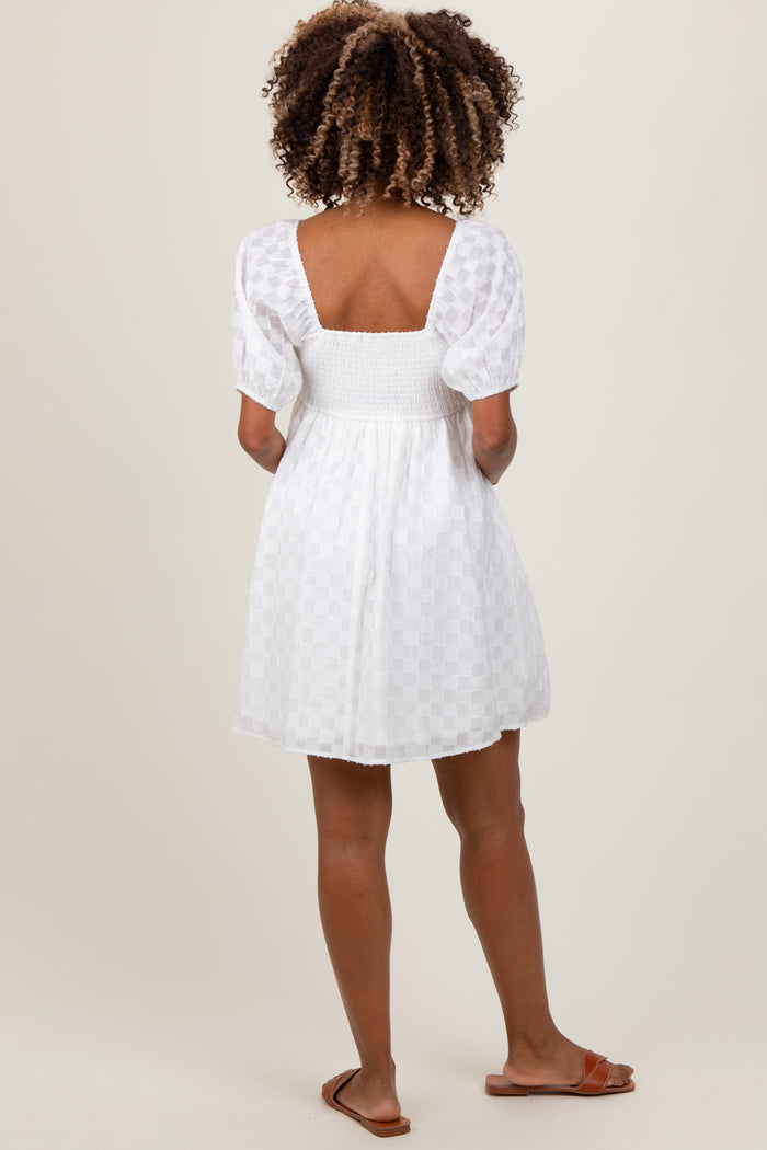 woman wearing a white maternity dress with a smocked bodice and puff sleeves, showing her back