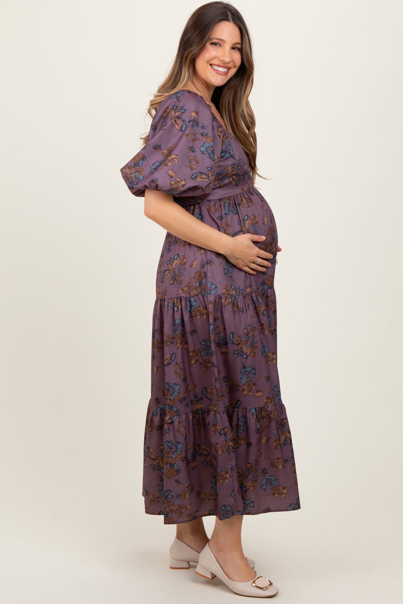 woman wearing a purple floral maternity maxi dress and holding her baby bump