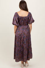 woman wearing a floral patterned maternity maxi dress with puff sleeves, showing the back view and a baby bump