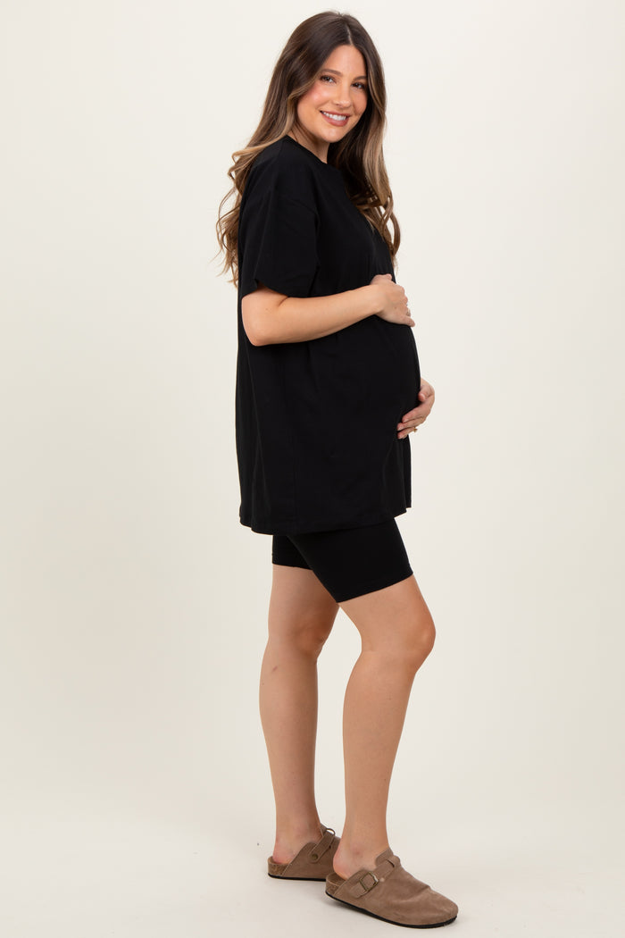woman wearing a black oversized maternity t-shirt and black bike shorts, showing her baby bump