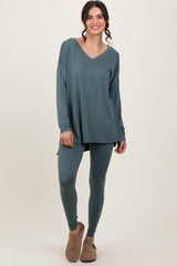 woman wearing a teal long sleeve v-neck top and matching leggings, styled with casual footwear