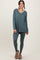woman wearing a teal long sleeve v-neck top and matching leggings, styled with casual footwear