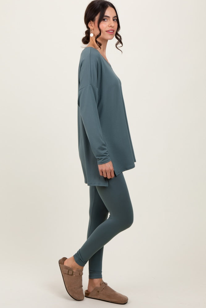 woman wearing a teal oversized long sleeve top and matching leggings, styled with brown slip-on shoes