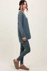 woman wearing a teal oversized long sleeve top and matching leggings, styled with brown slip-on shoes