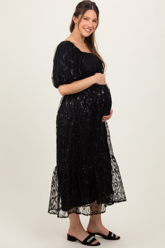 woman wearing a black embroidered maternity dress with puff sleeves and a baby bump