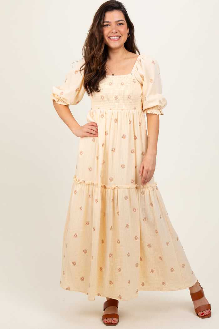 woman wearing a cream floral maxi dress with puff sleeves and a smocked bodice, standing on a neutral background
