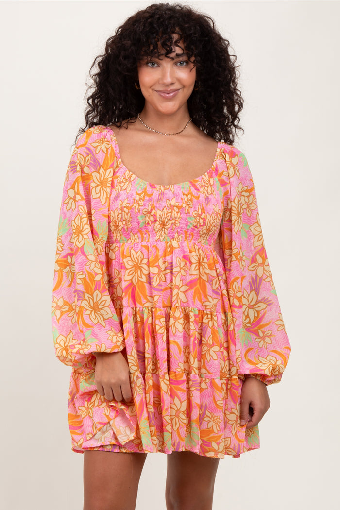 woman wearing a floral pink and orange smocked mini dress with long sleeves