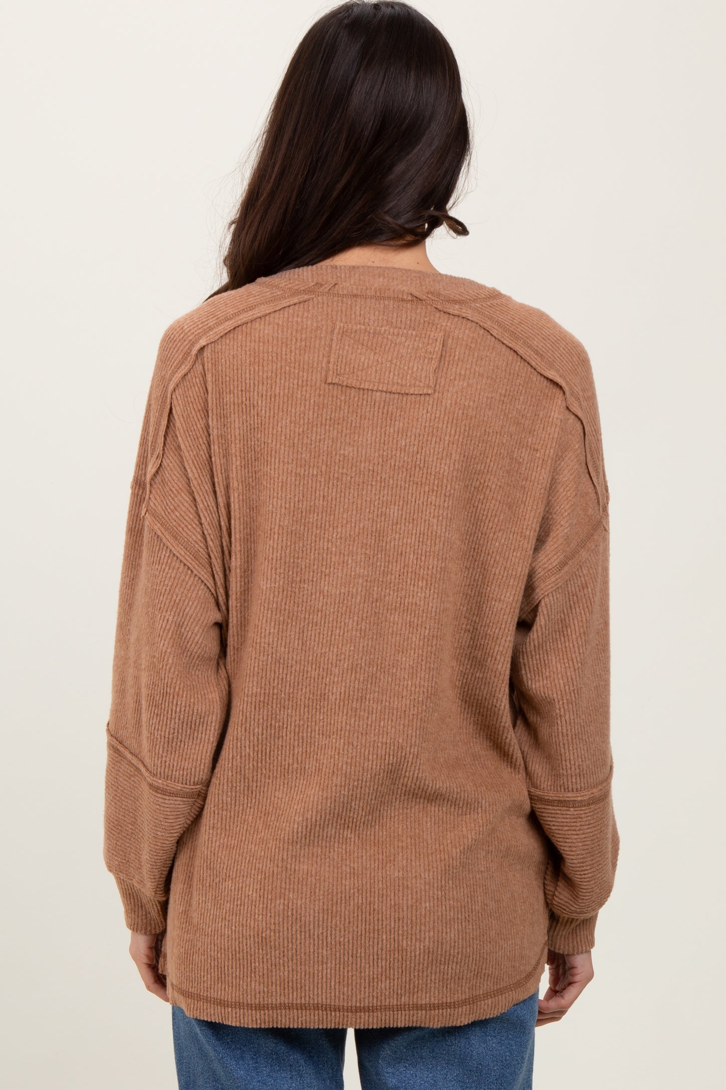 woman wearing a brown oversized ribbed sweater, showing the back view with relaxed fit and long sleeves