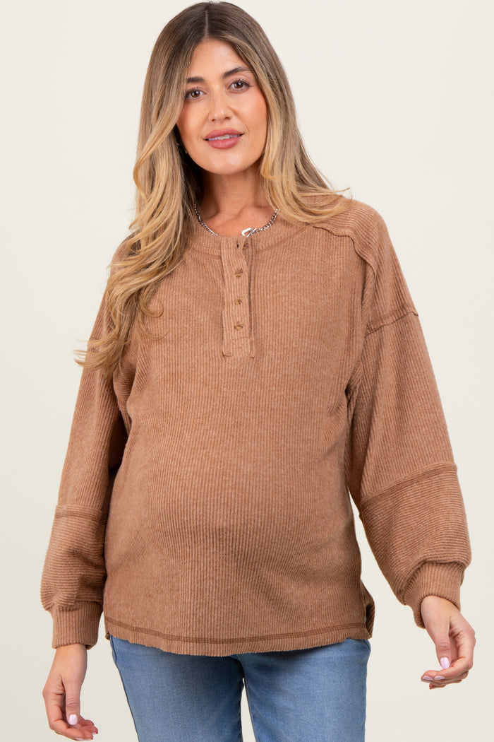 woman wearing a brown ribbed maternity sweater with a button-up neckline and a visible baby bump