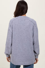 woman wearing a loose-fitting light gray oversized sweater with ribbed texture and dropped shoulder seams