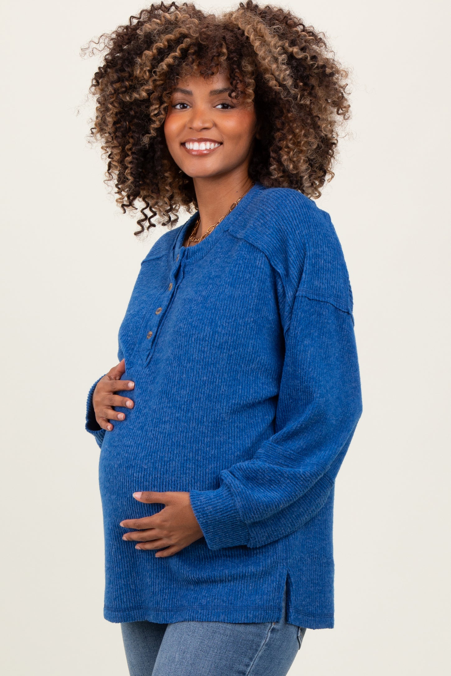woman wearing a blue long sleeve maternity top with button details and a visible baby bump
