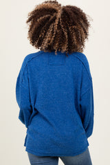 woman wearing a blue oversized maternity sweater, seen from the back, with a relaxed fit and ribbed texture