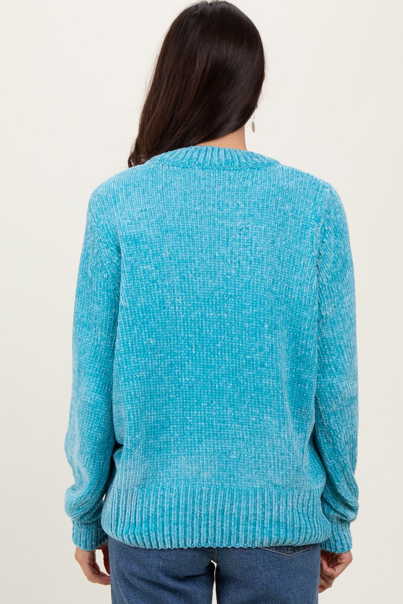 woman wearing a turquoise knit sweater with long sleeves and a ribbed hem, shown from the back
