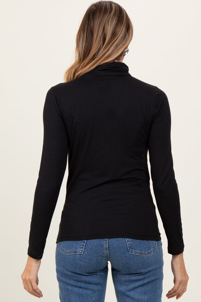 woman wearing a black long sleeve turtle neck top with a fitted style and back view, paired with blue jeans
