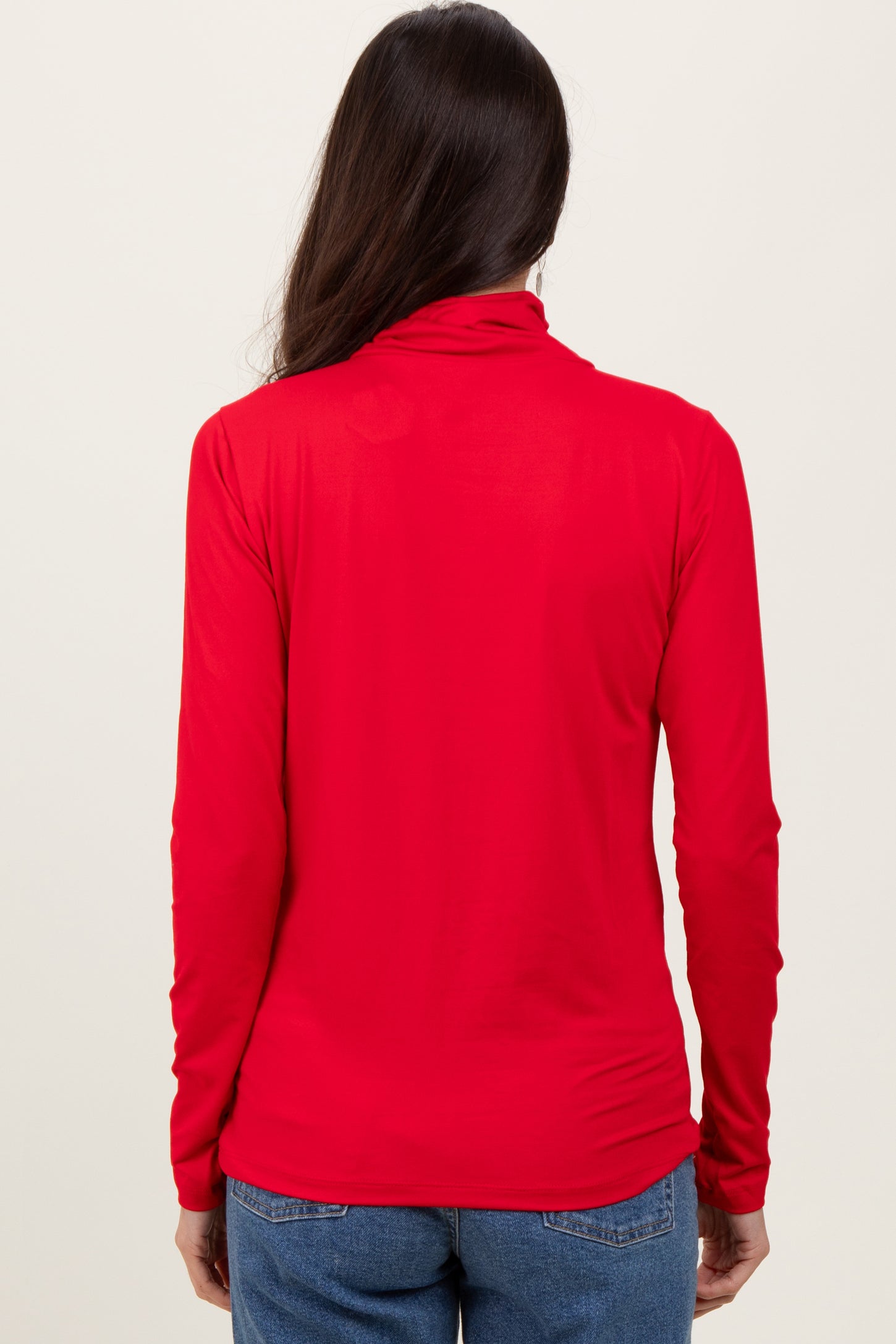 woman wearing a red long sleeve top viewed from the back with a mock neck and fitted style