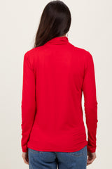 woman wearing a red long sleeve top viewed from the back with a mock neck and fitted style