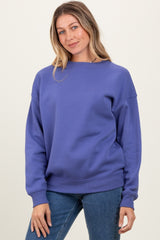 woman wearing a purple oversized sweatshirt with a crew neck and relaxed fit, paired with blue jeans