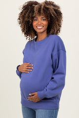 woman wearing a purple oversized maternity sweatshirt and holding her baby bump