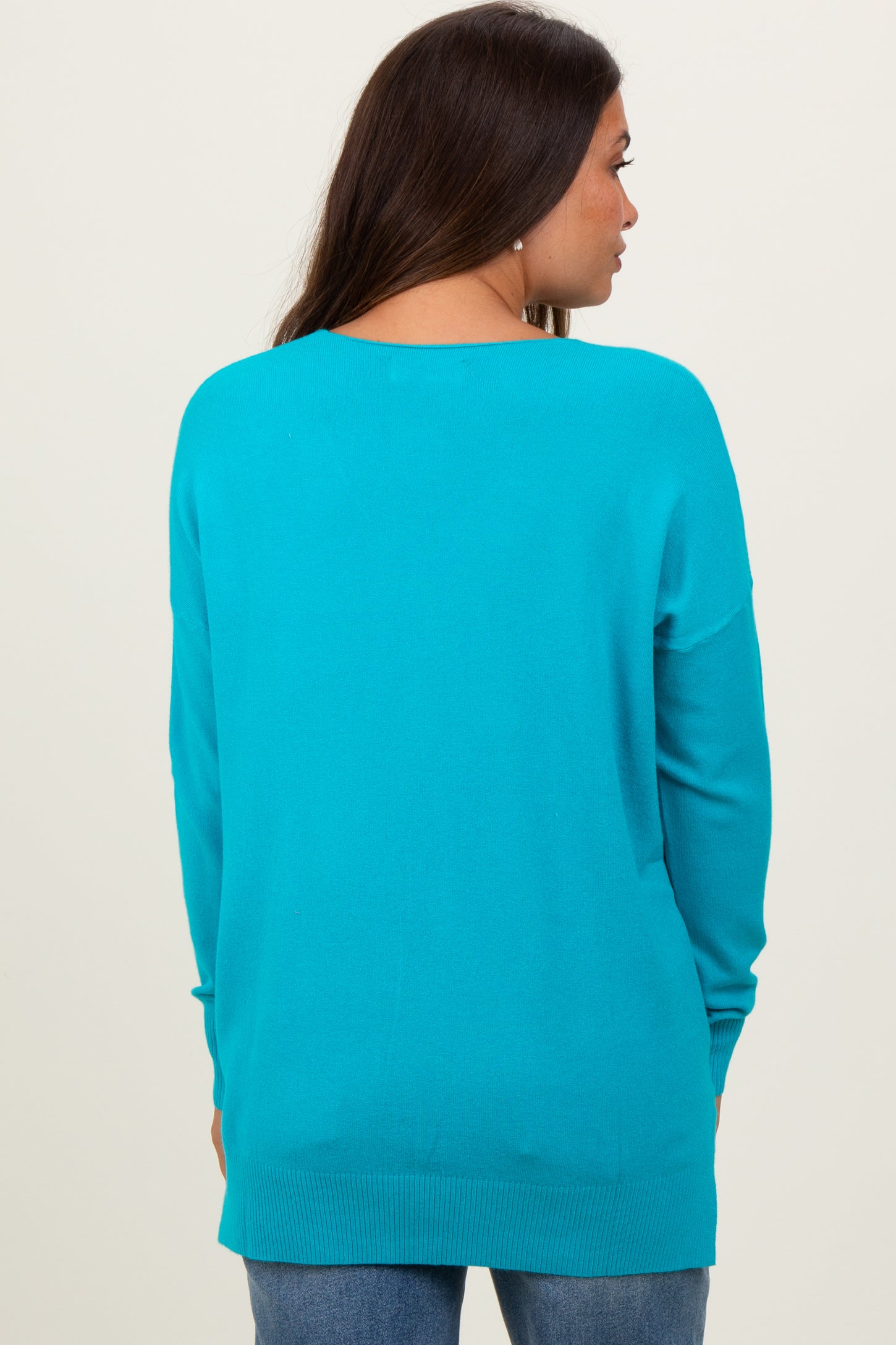 woman wearing a vibrant turquoise maternity sweater, shown from the back, with relaxed fit and long sleeves