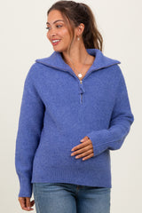 woman wearing a purple maternity sweater with a zip collar and a relaxed fit, gently cradling her baby bump