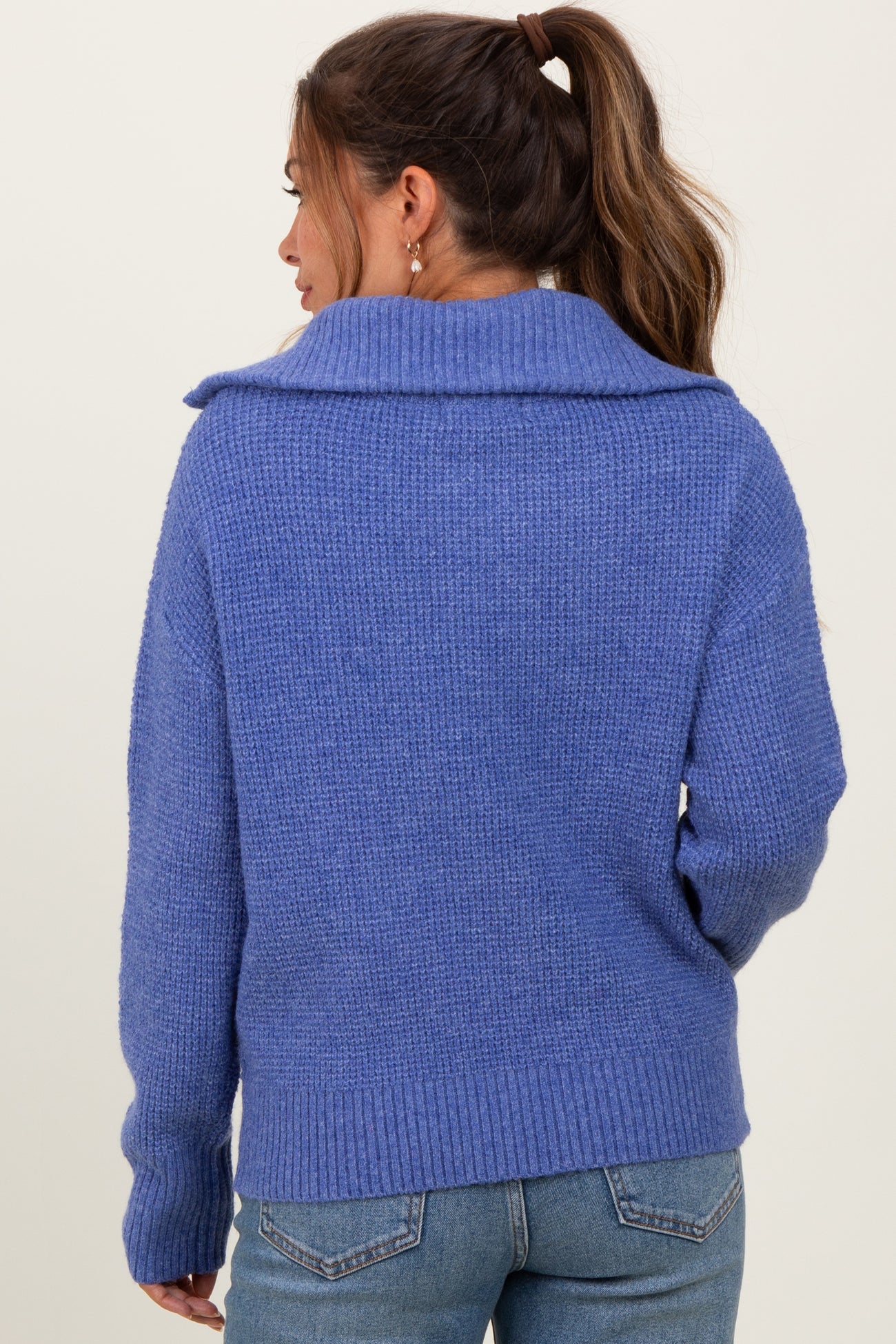 woman wearing a cozy blue maternity sweater with a wide collar and ribbed hem, showcasing a relaxed fit from the back