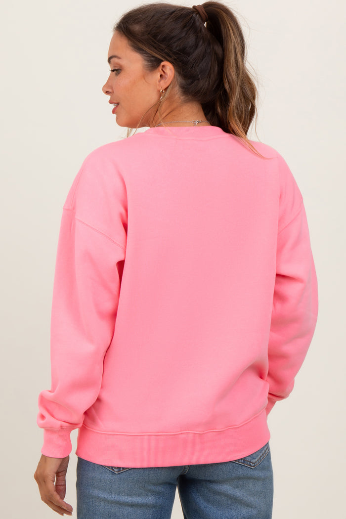 woman wearing a bright pink maternity sweatshirt with a relaxed fit and long sleeves, showing her back