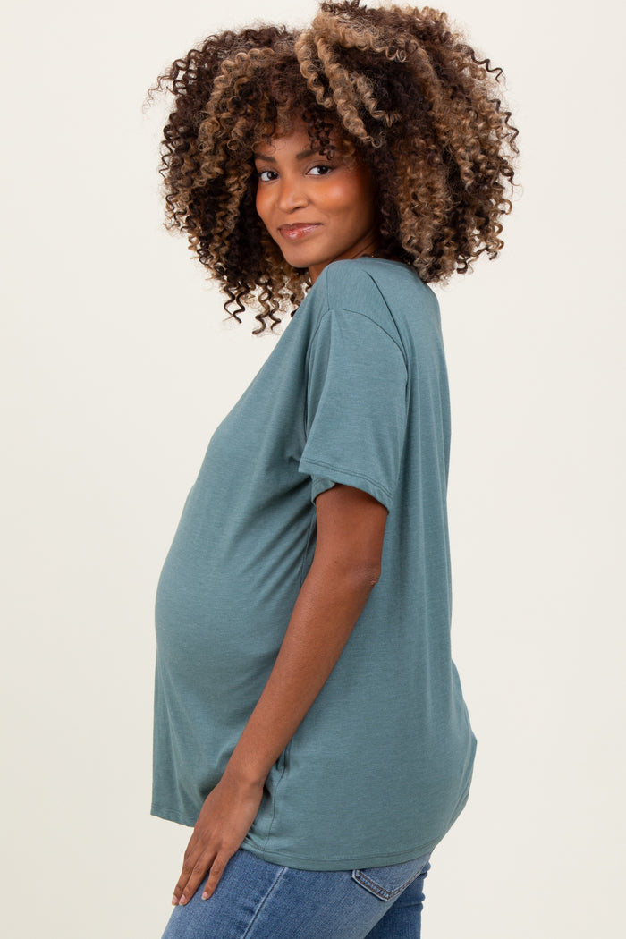woman wearing a teal short sleeve maternity top and showing her baby bump