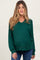 woman wearing a dark green v-neck maternity sweatshirt with long sleeves and a visible baby bump