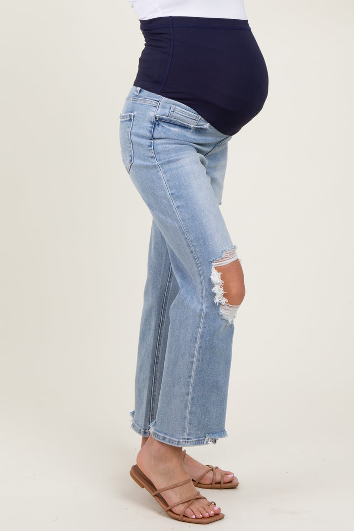 woman wearing light blue distressed maternity jeans with a navy waistband and visible baby bump