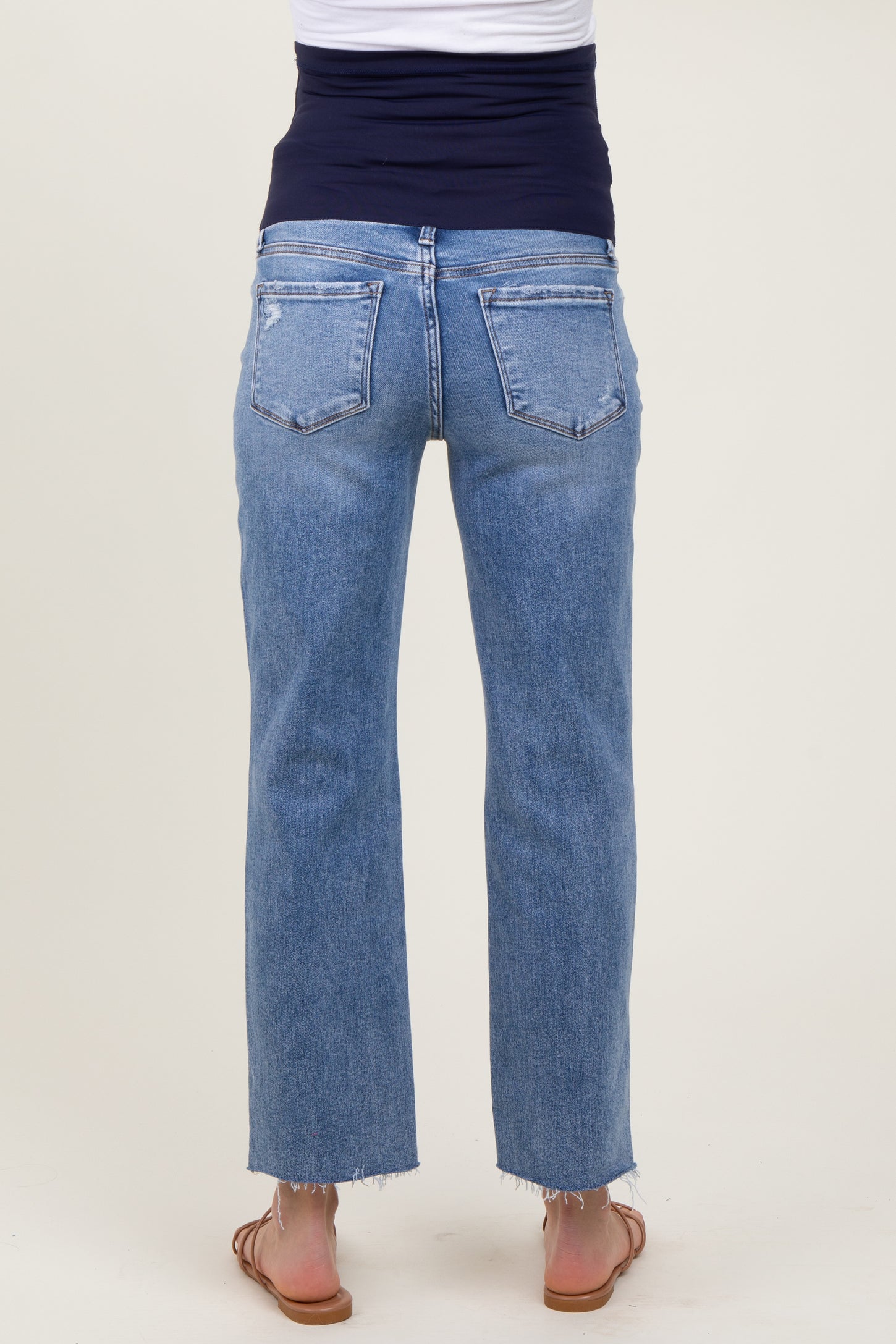 maternity wear light blue cropped jeans with a distressed hem and stretchy waistband, shown from the back