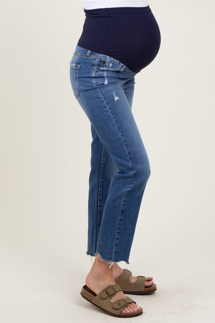 woman wearing dark blue maternity jeans with a distressed hem and a navy over-the-belly waistband, showing her baby bump