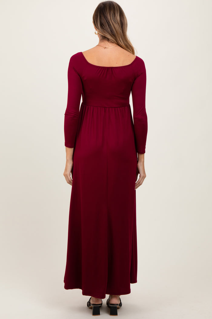 woman wearing a burgundy long sleeve maxi dress with a scoop back and fitted bodice