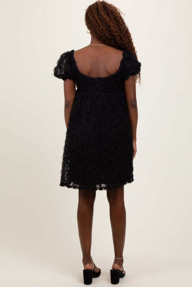 woman wearing a black short sleeve dress with floral lace detailing and a scoop back, standing with her back facing the camera