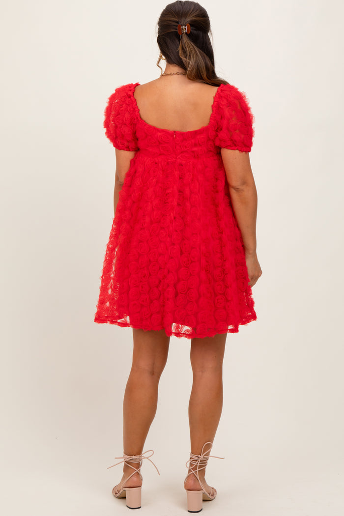 woman wearing a red maternity dress with textured floral details and puff sleeves, showing a baby bump