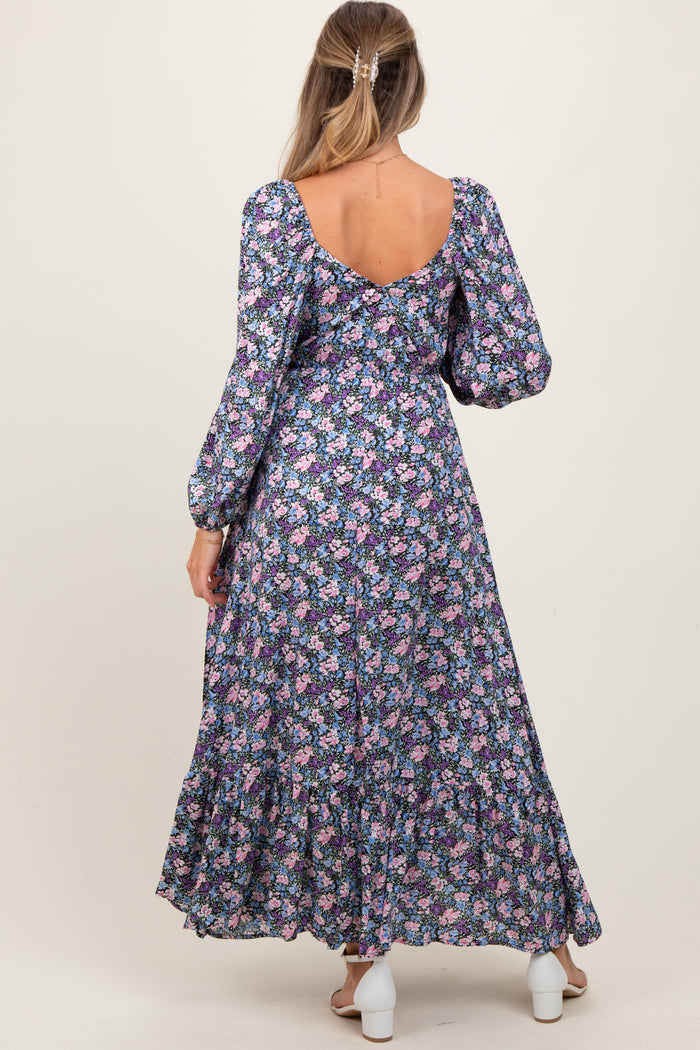 woman wearing a floral maternity maxi dress with long sleeves and a ruffled hem, showing a baby bump from the back