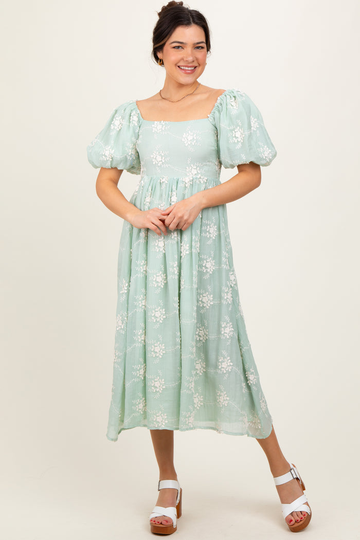 woman wearing a mint green floral midi dress with puff sleeves and a square neckline