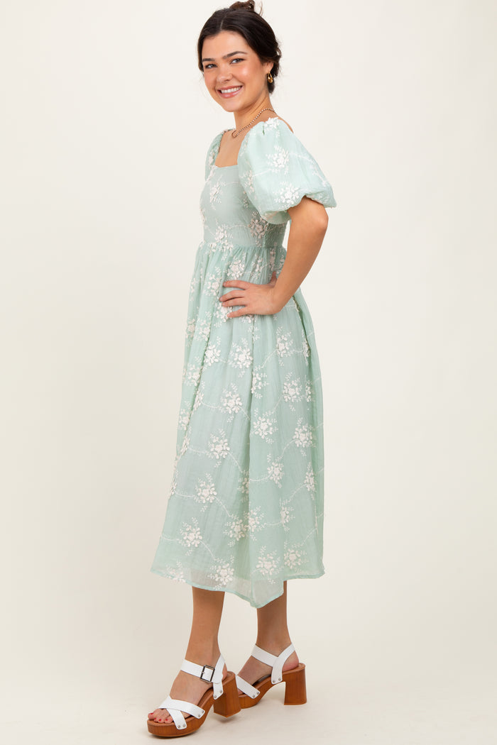 woman wearing a light green floral midi dress with puff sleeves and a square neckline