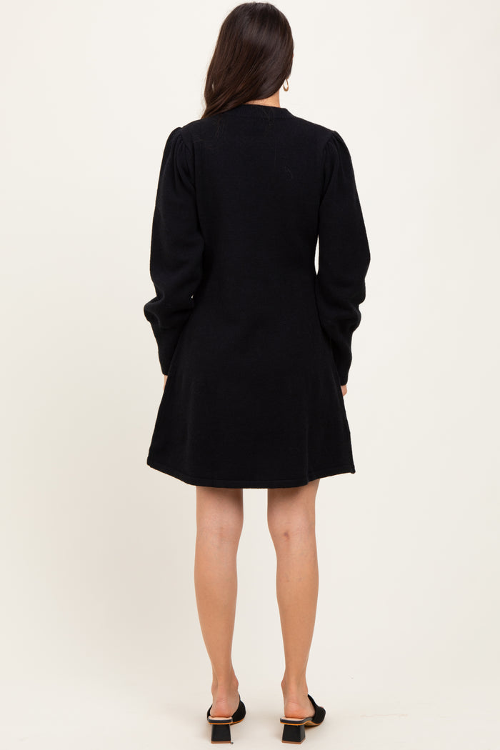 woman wearing a black long sleeve dress with a fitted bodice and flared skirt, viewed from the back