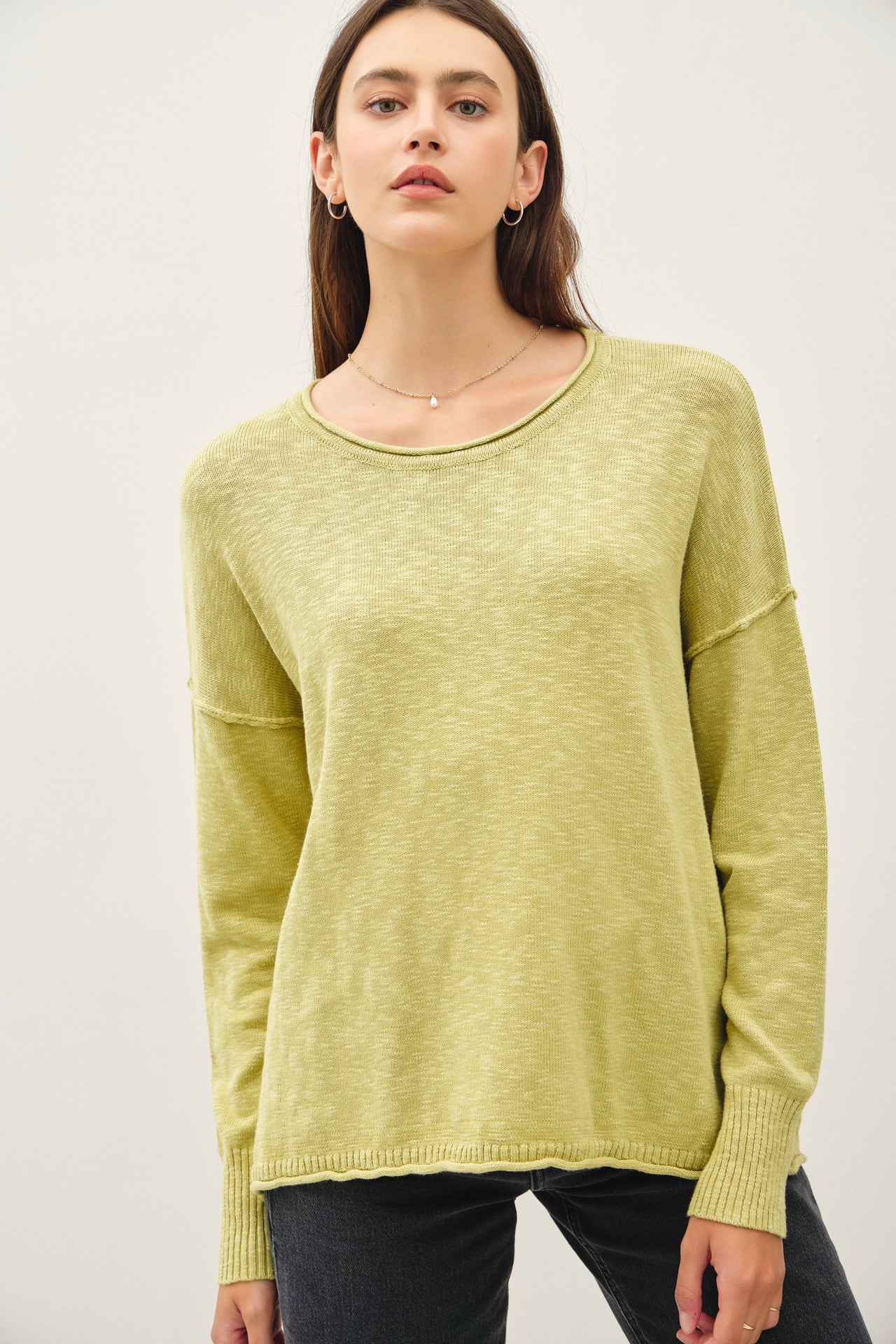 woman wearing a light green long sleeve sweater with a relaxed fit and ribbed cuffs