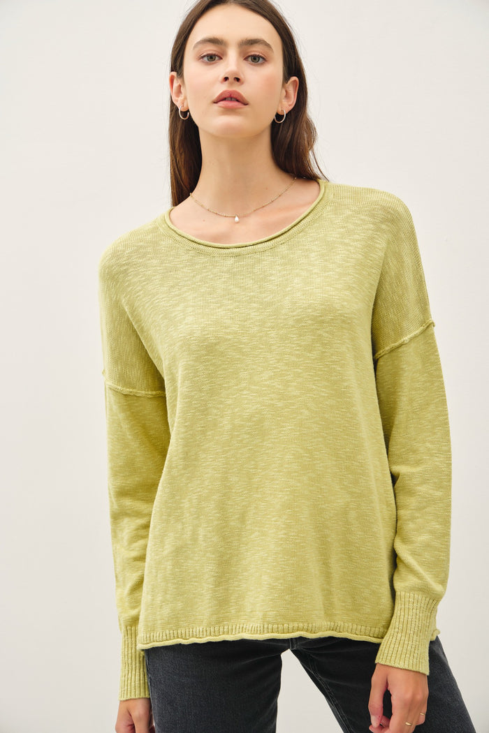 woman wearing a light green long sleeve sweater with a relaxed fit and ribbed cuffs