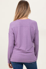 woman wearing a purple long sleeve maternity top, viewed from the back, paired with blue jeans