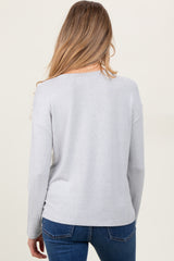 woman wearing a light gray maternity pullover sweater, viewed from the back, paired with blue jeans