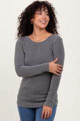 woman wearing a gray ribbed long sleeve top and smiling, with loose curls and gold earrings
