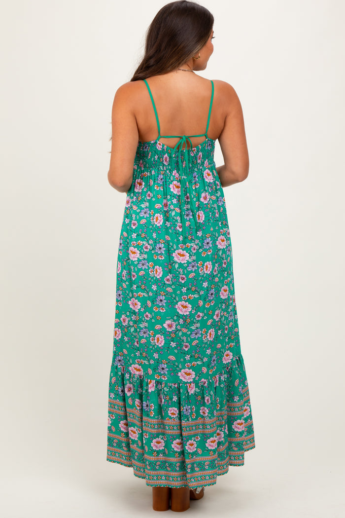 woman wearing a green floral maternity maxi dress with a tie-back and tiered skirt, showing a baby bump from the back