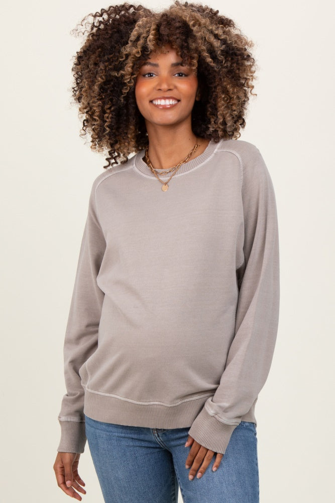 woman wearing a light grey maternity sweater with a relaxed fit and long sleeves, smiling and showing her baby bump