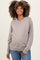 woman wearing a light grey maternity sweater with a relaxed fit and long sleeves, smiling and showing her baby bump