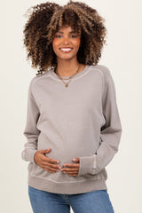 woman wearing a light gray maternity sweatshirt and holding her baby bump